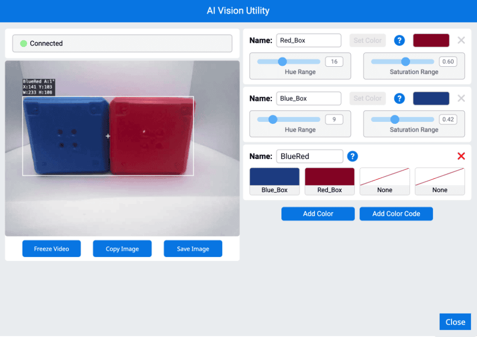 The AI Vision Utility interface shows a connected vision sensor detecting two adjacent objects, a blue box on the left and a red box on the right, grouped together in a single white bounding box labeled BlueRed. Detection information includes angle (A:11°), coordinates (X:143, Y:103), width (W:233), and height (H:108). On the right panel, three color signatures are listed: Red_Box, Blue_Box, and BlueRed, with adjustable hue and saturation ranges. The BlueRed signature combines the Blue_Box and Red_Box. Below the video feed are buttons labeled Freeze Video, Copy Image, Save Image, and Close.
